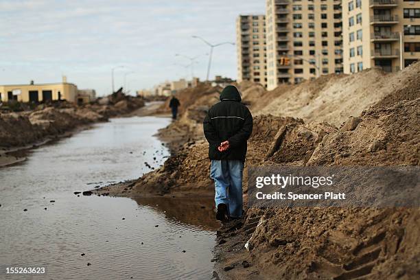 People walk through the heavily damaged Rockaway neighborhood, in Queens where a large section of the iconic boardwalk was washed away on November 2,...