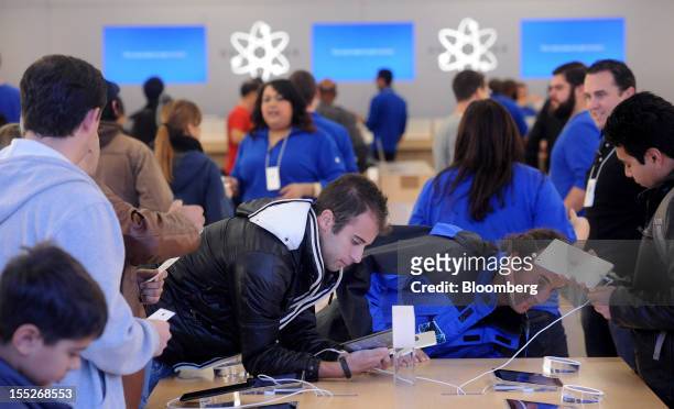Shoppers at an Apple Inc. Retail store examine an iPad mini during the first day of sales in San Francisco, California, U.S. On Friday, Nov. 2, 2012....