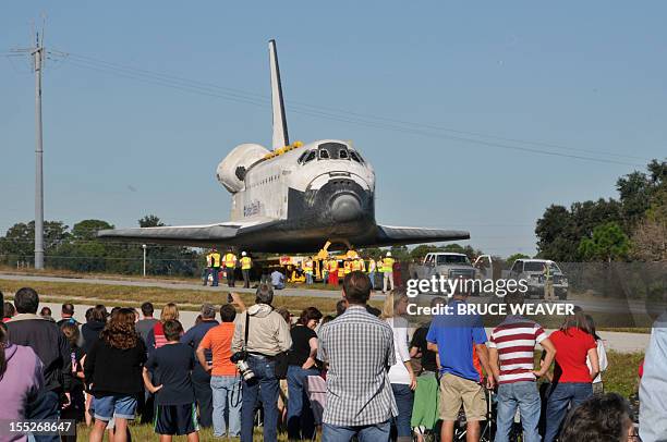 Workers and visitors watch the US Space Shuttle Atlantis moves on November 2, 2012 to the Visitors Center at Kennedy Space Center in Cape Canaveral,...
