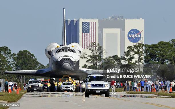 Workers and visitors watch the US Space Shuttle Atlantis moves on November 2, 2012 to the Visitors Center at Kennedy Space Center in Cape Canaveral,...