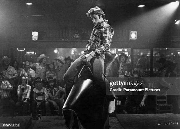 American actor John Travolta rides a bucking bronco machine in a scene from the film 'Urban Cowboy', 1980.