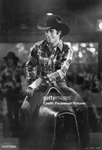 American actor John Travolta rides a bucking bronco machine in a scene from the film 'Urban Cowboy', 1980.