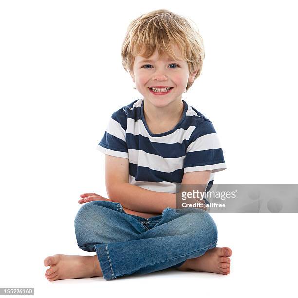 small boy sitting crossed legged smiling on white - sit in stockfoto's en -beelden