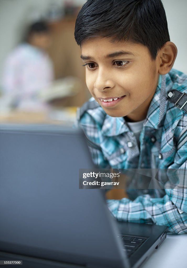 Close-up of a happy, Indian boy using laptop