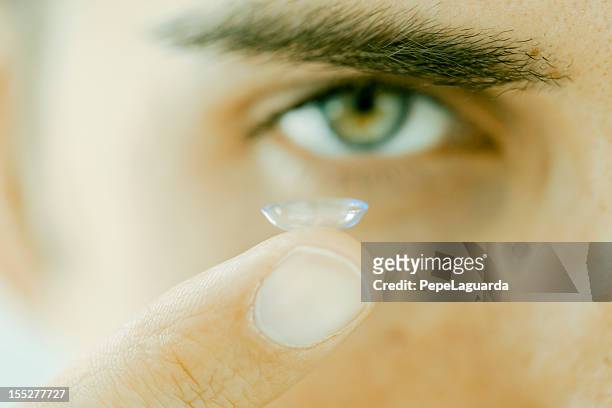 vision: mann mit einer kontaktlinse - contacts stock-fotos und bilder