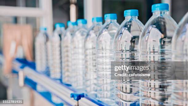 water bottles on an automated conveyor belt - plastic water bottle stock pictures, royalty-free photos & images