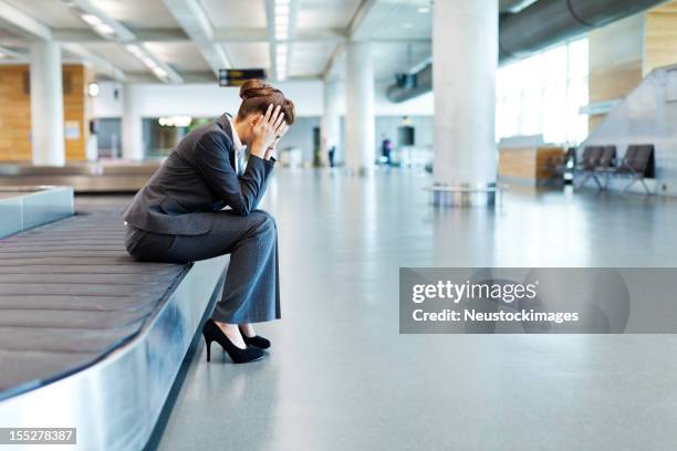 frustrated businesswoman sitting at baggage claim - airport frustration stock pictures, royalty-free photos & images