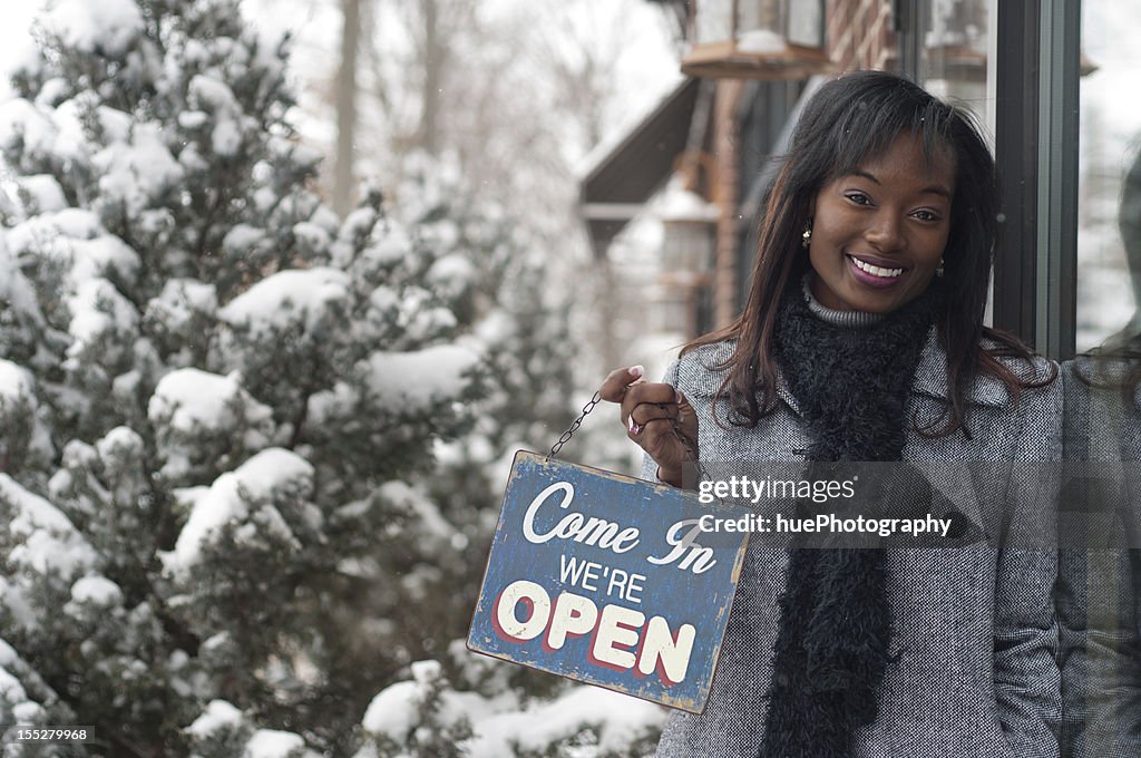 Woman holding a Come In We're Open sign