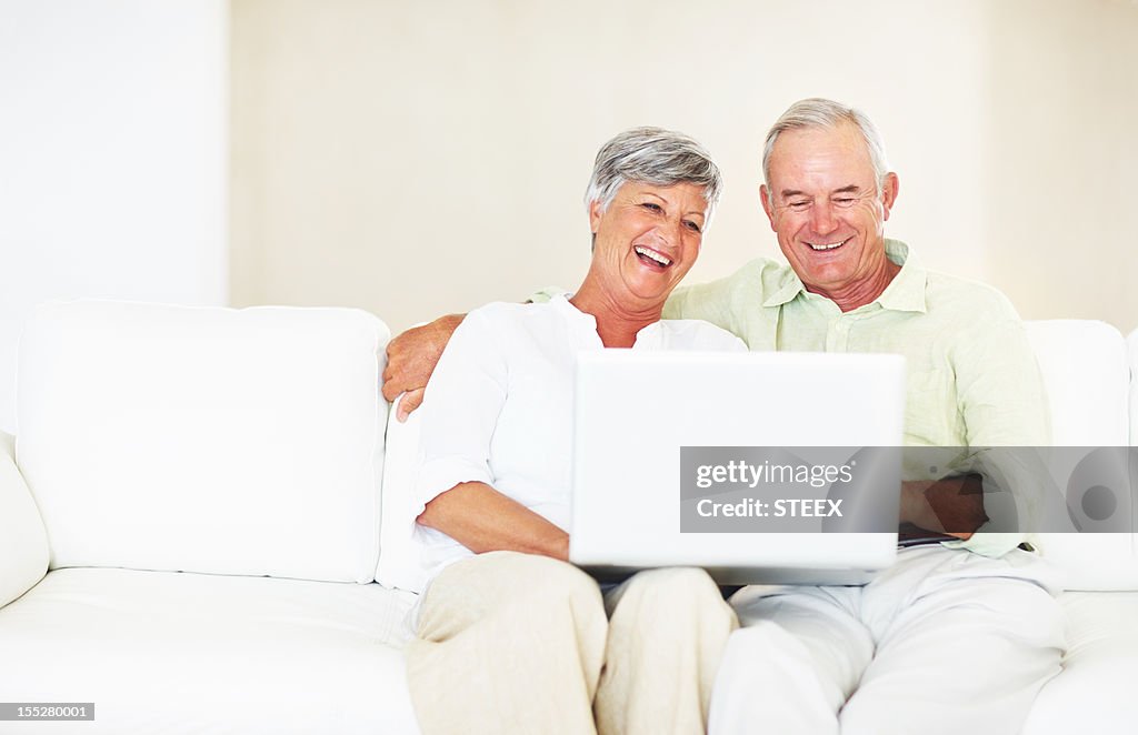 Mature couple using laptop on couch