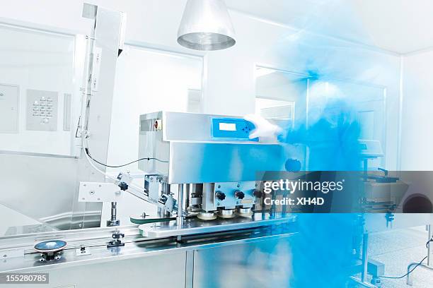 pharmaceutical equipment with technician in blue - pharmaceutical manufacturing machine stock pictures, royalty-free photos & images