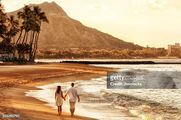 coppia felice a piedi all'alba sulla spiaggia di waikiki - viaggio di nozze foto e immagini stock