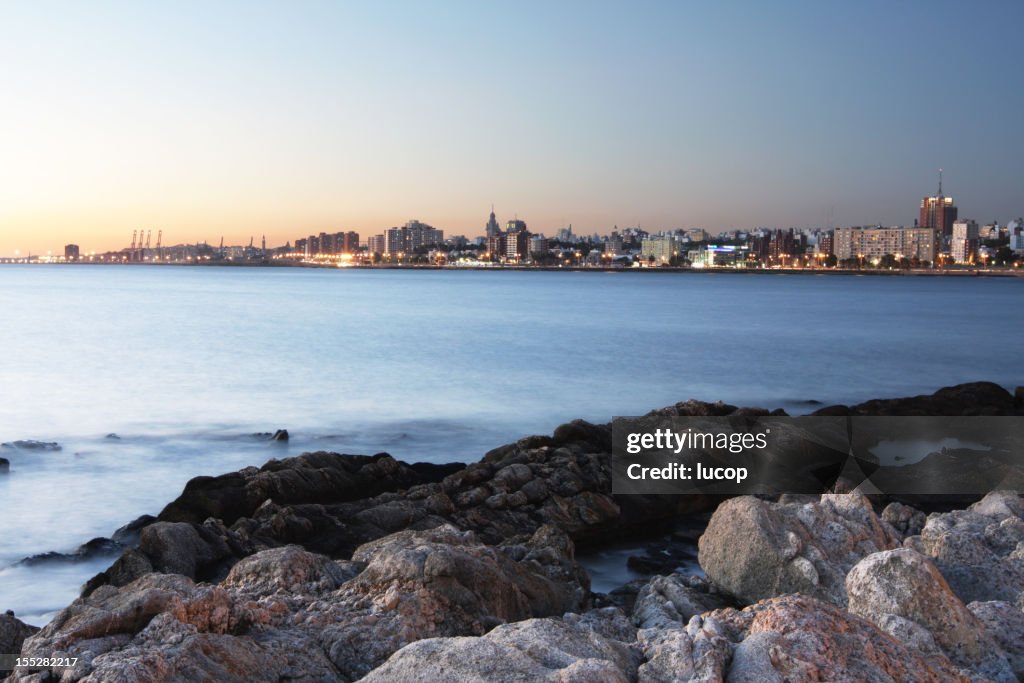 Montevideo city scape con rocas en la playa al atardecer