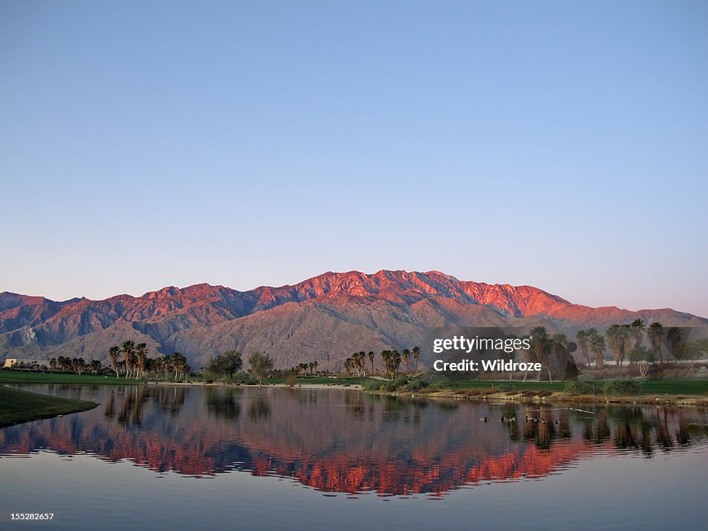 Golf course at dawn with sunrise kissed mountains