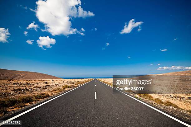 long road in the desert heading into a blue sky - desert highway stock pictures, royalty-free photos & images
