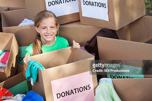 young girl in the middle of many donation boxes - clothing donations stock pictures, royalty-free photos & images