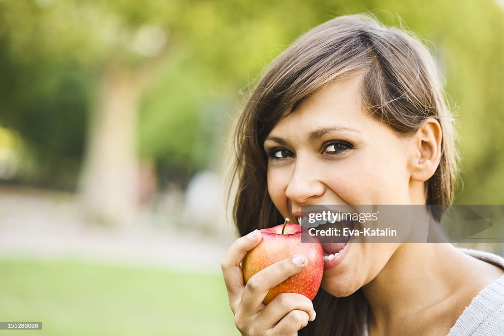 Cheerful young woman eating an apple