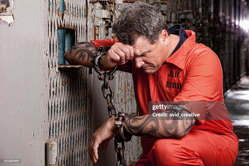 Prisioneiro no seu joelhos para orar prisão