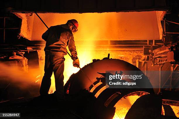 foundry worker shoveling molten metal in a furnace - steel factory stock pictures, royalty-free photos & images
