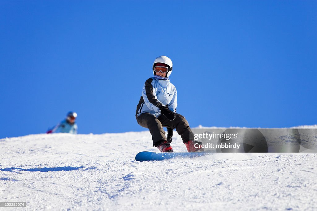 Teenage girl snowboarding on sunny winter day