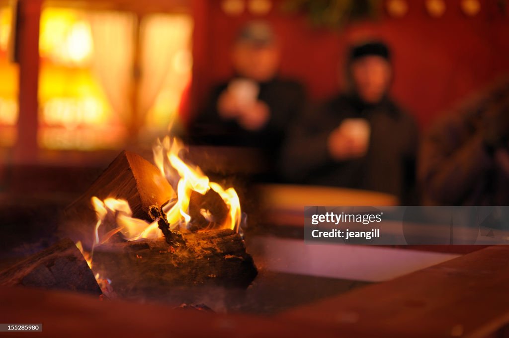 Homeless couple by log fire outdoors
