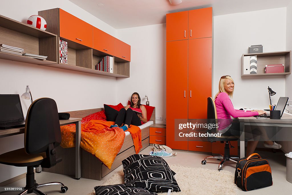 Female teenagers reading books and using the laptop