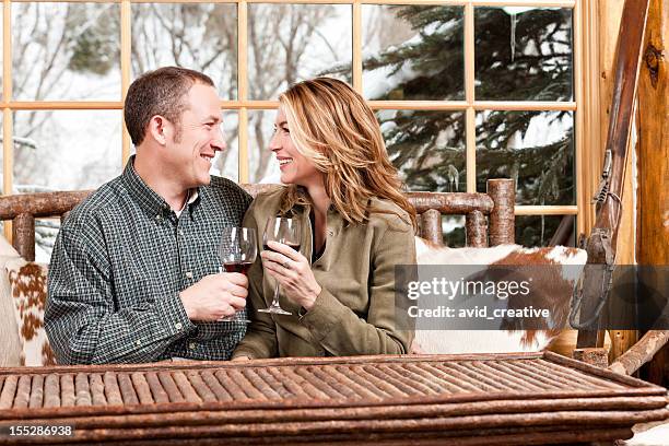 happy couple drinking wine in ski lodge - ski lodge wine stock pictures, royalty-free photos & images