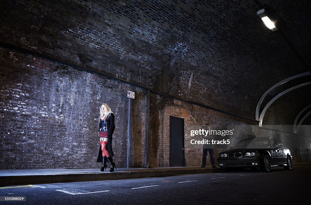 Couple playing master and servant in a dark highway tunnel.