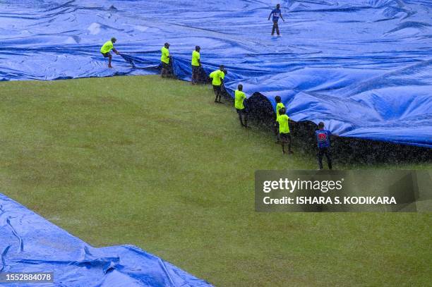 Members of ground staff cover the pitch as rain stops the second day play of the second and final cricket Test match between Pakistan and Sri Lanka...