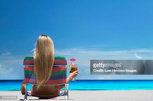 woman relaxing in lawn chair on beach - mai tai stock-fotos und bilder