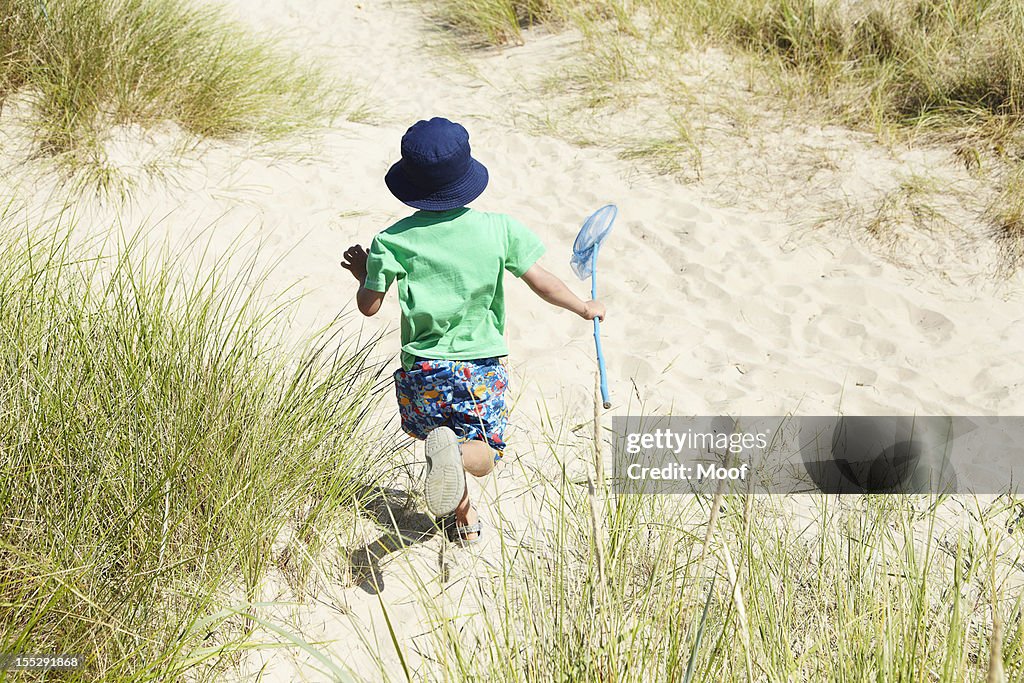 Boy carrying fishing net on beach