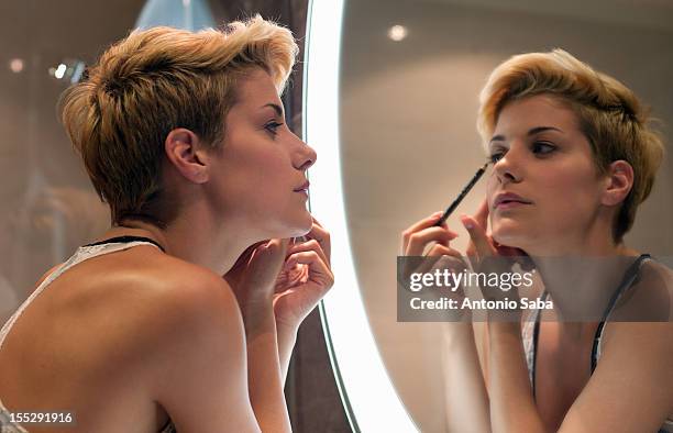 woman applying makeup in mirror - kajalschminke stock-fotos und bilder