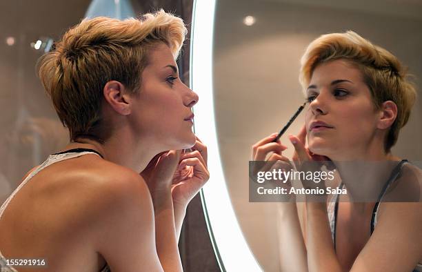 woman applying makeup in mirror - eyeliner ストックフォトと画像