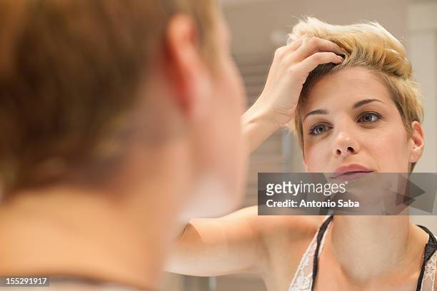 woman examining herself in mirror - 鏡　女性 ストックフォトと画像