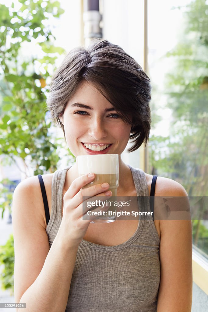 Smiling woman drinking coffee outdoors