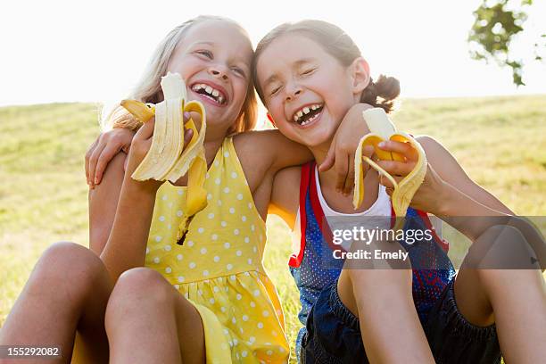 laughing girls eating bananas outdoors - bavaria girl stock pictures, royalty-free photos & images