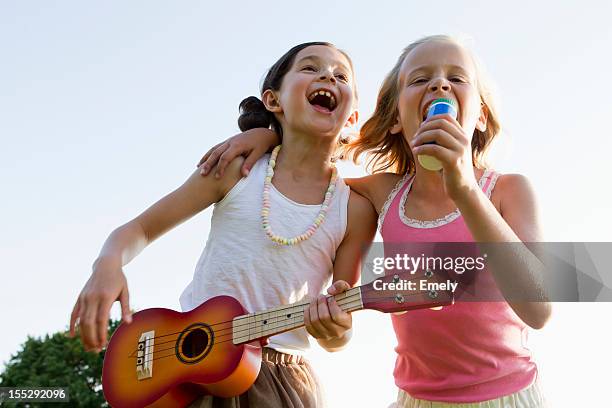 girls singing together outdoors - saiteninstrument spielen stock-fotos und bilder