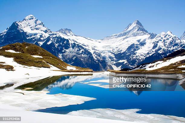 snowy landscape reflected in still lake - schweizer alpen stock-fotos und bilder