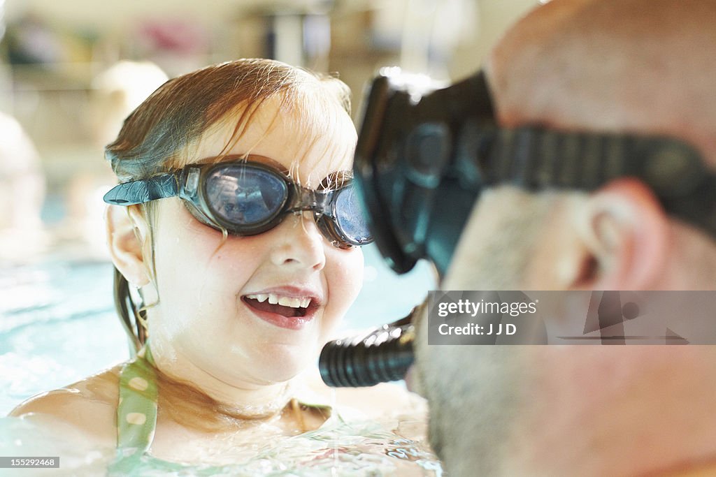 Father and daughter swimming in pool