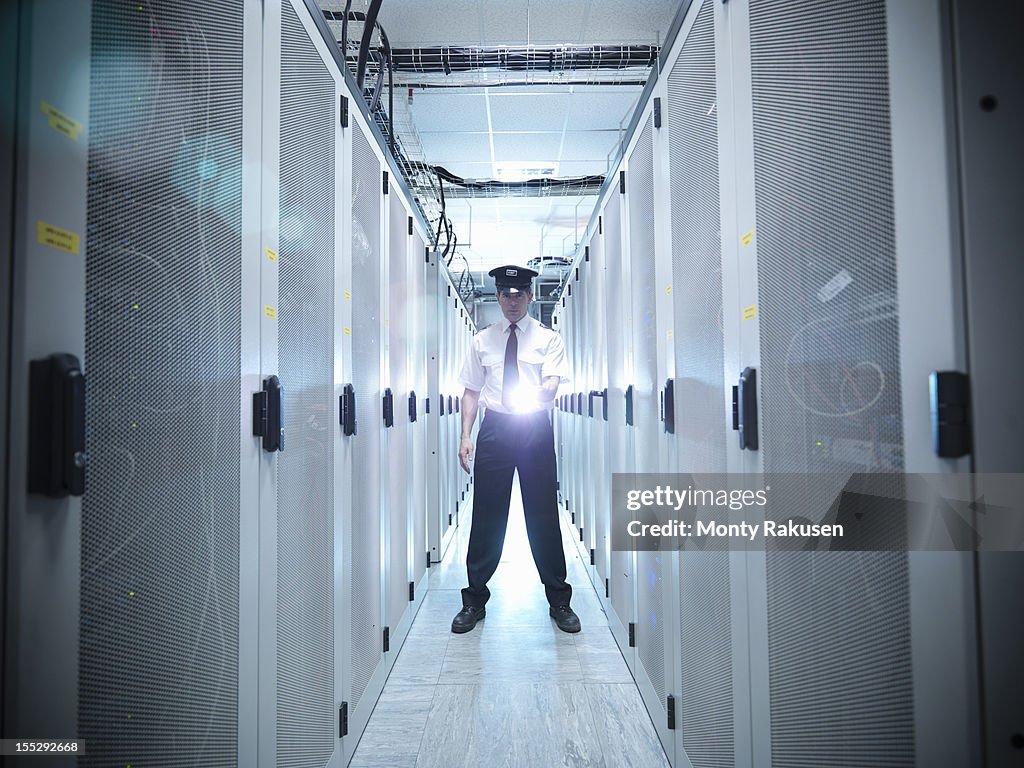 Portrait of security guard shining torch in computer server room