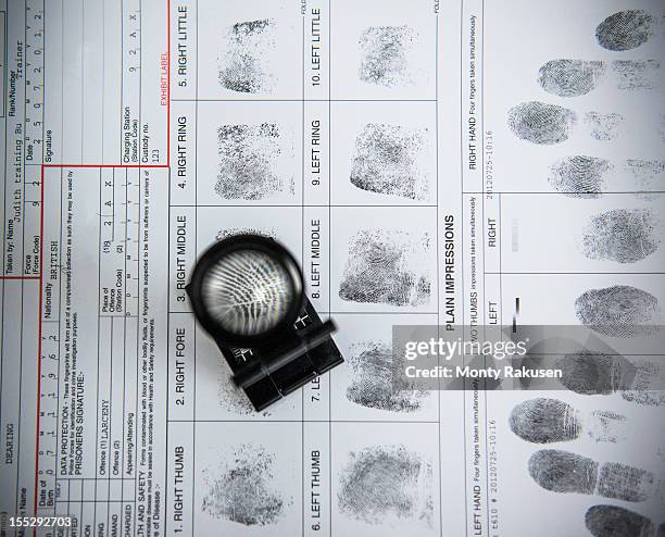fingerprints with loupe on arrest form in forensic laboratory - crimen fotografías e imágenes de stock