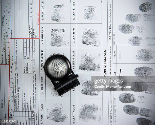 fingerprints with loupe on arrest form in forensic laboratory - forensisch onderzoek stockfoto's en -beelden