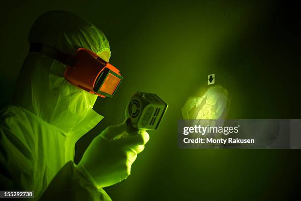forensic scientist using finger print light to find hand print on wall at crime scene - forensisch onderzoek stockfoto's en -beelden