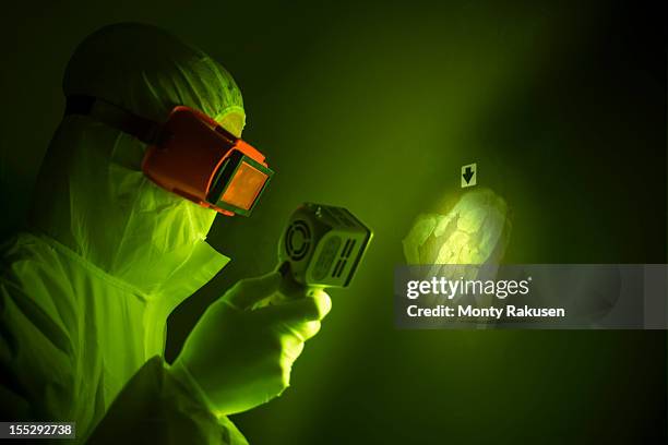 forensic scientist using finger print light to find hand print on wall at crime scene - forensic stock pictures, royalty-free photos & images