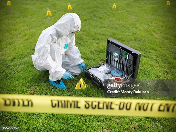 forensic scientist inspecting toolkit at crime scene, police tape in foreground - forens fotografías e imágenes de stock