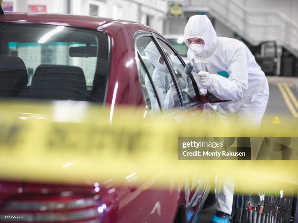 Forensic scientist dusting car for finger prints at crime scene