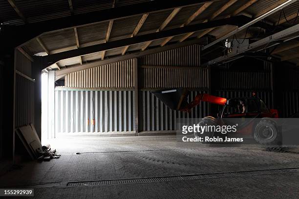 farmer driving digger in shed - shed stock pictures, royalty-free photos & images
