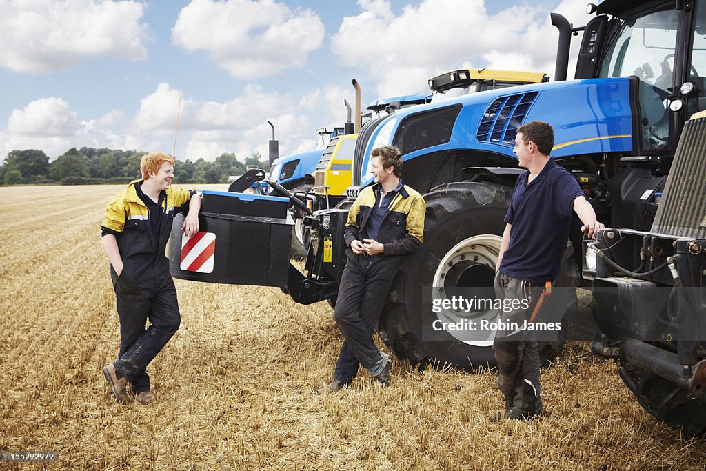 Farmers talking by machinery in field