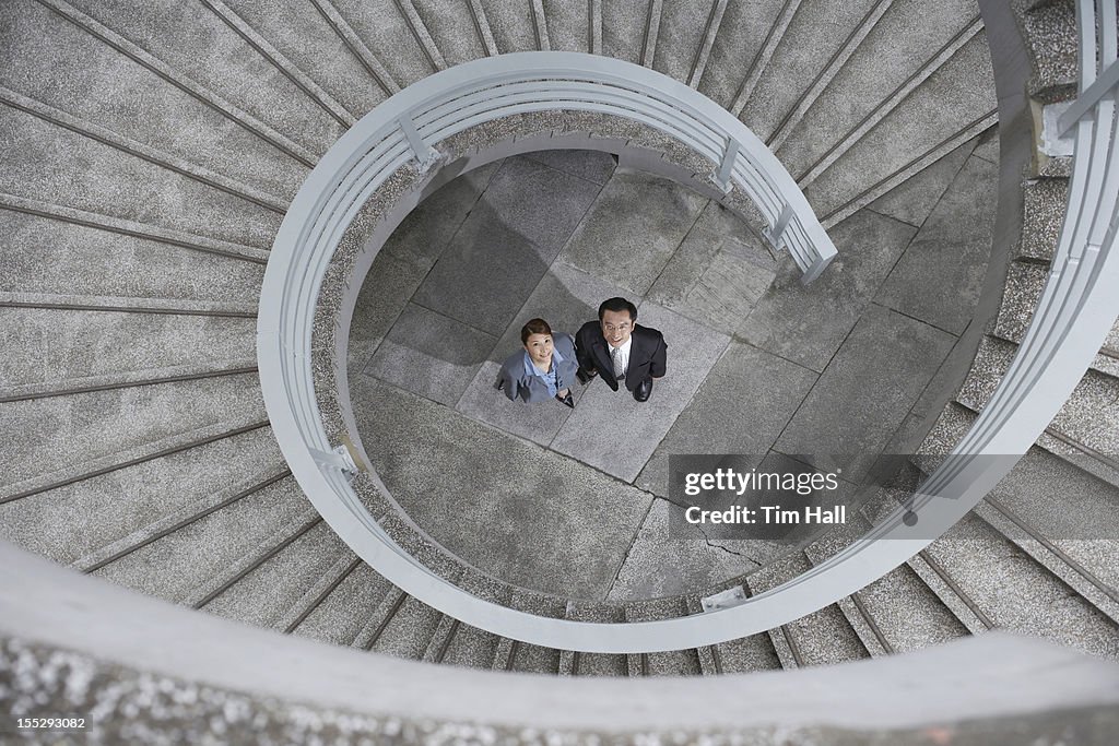 Business people under spiral staircase