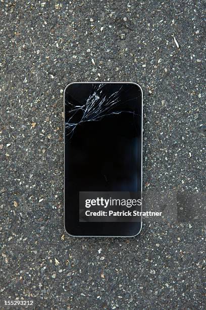 a smart phone with a cracked screen - broken phone stock-fotos und bilder