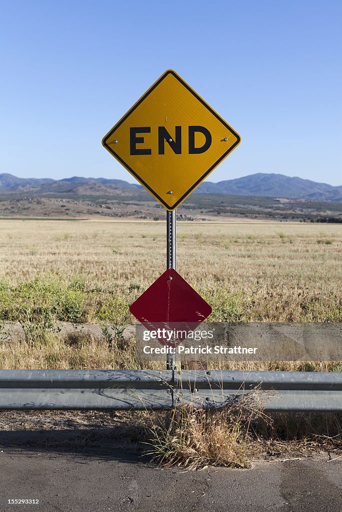 An END road sign and mountain ranges behind